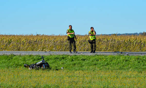 Des policiers de la Sûreté du Québec devant la motocyclette accidentée.
