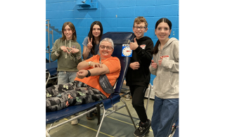 Louise Carrier, qui a fait son 120e don de sang, entouré des élèves de 6e années de l’école Jacques-de-Chambly (Photo: courtoisie, Héma-Québec)
